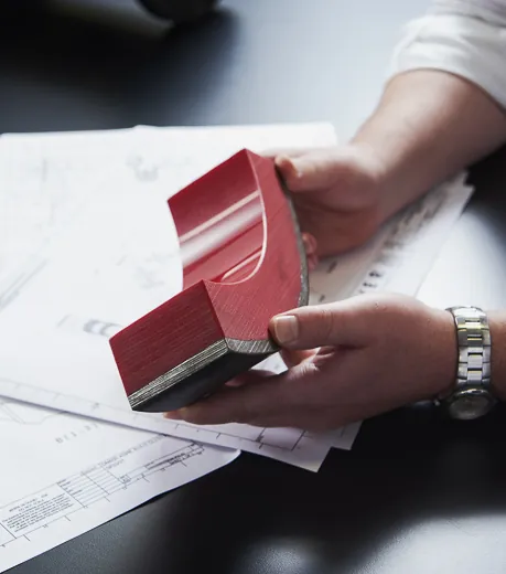 Hand holding a slurry pipeline material sample over engineering drawings