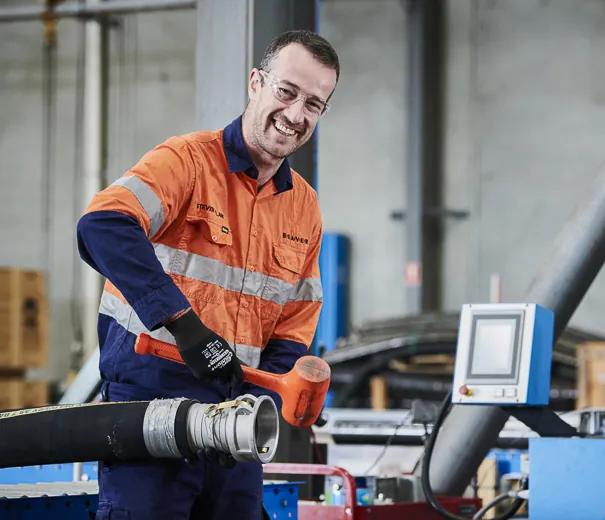 Beaver fabricator inspecting a custom slurry hose assembly in the workshop