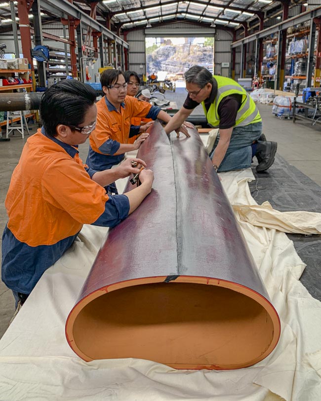 A team of workers preparing rubber lining for a pipe