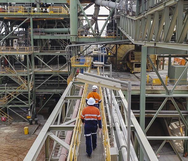 2 people walking through processing plant to inspect slurry piping