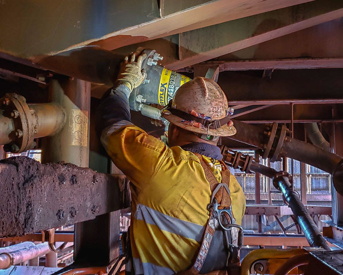 A worker fitting a flexible Slurryflex hose spool in a processing plant